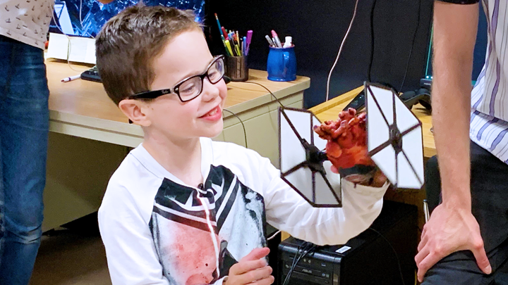 Heart transplant recipient Mason Thomas, 8, shows off a 3D model of his old heart, complete with Star Wars TIE fighter wings.
