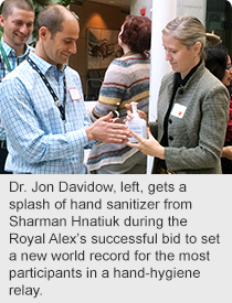 Dr. Jon Davidow, left, gets a splash of hand sanitizer from Sharman Hnatiuk during the Royal Alex’s successful bid to set a new world record for the most participants in a hand-hygiene relay.