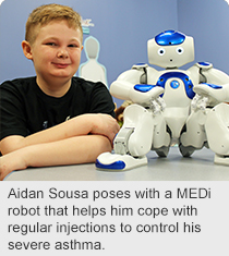 Aidan Sousa poses with a MEDi robot that helps him cope with regular injections to control his severe asthma.