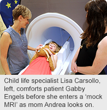 Child life specialist Lisa Carsollo, left, comforts patient Gabby Engels before she enters a ‘mock MRI’ as mom Andrea looks on.