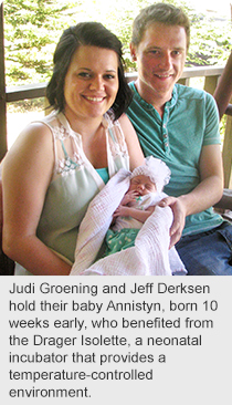 Judi Groening and Jeff Derksen hold their baby Annistyn, born 10 weeks early, who benefited from the Drager Isolette, a neonatal incubator that provides a temperature-controlled environment.