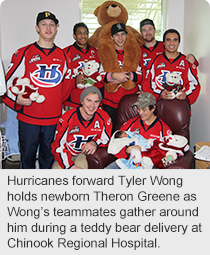 Hurricanes forward Tyler Wong holds newborn Theron Greene as Wong’s teammates gather around him during a teddy bear delivery at Chinook Regional Hospital.
