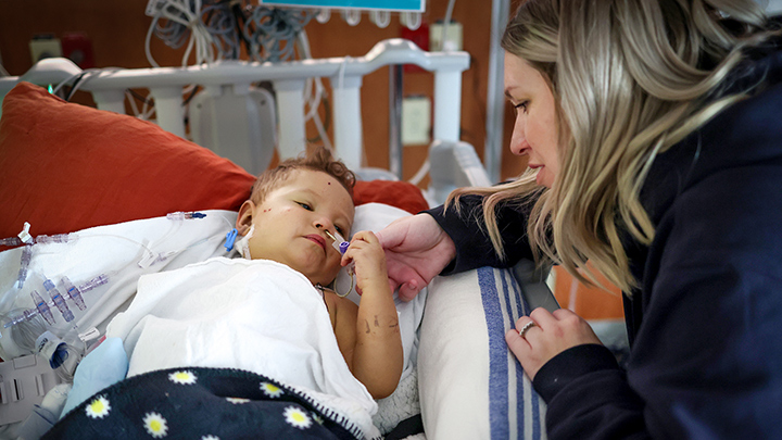 Colby and mom hold hands after his liver transplant.