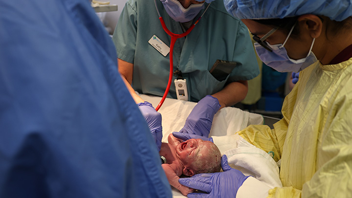 Surrounded by a team of experts, the baby takes in their first moments of life.
