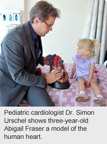 Pediatric cardiologist Dr. Simon Urschel shows three-year-old Abigail Fraser a model of the human heart. 