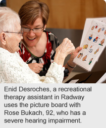 Enid Desroches, a recreational therapy assistant in Radway uses the picture board with Rose Bukach, 92, who has a severe hearing impairment.