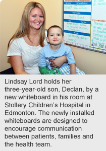 Lindsay Lord holds her three-year-old son, Declan, by a new whiteboard in his room at Stollery Children’s Hospital in Edmonton. The newly installed whiteboards are designed to encourage communication between patients, families and the health team.