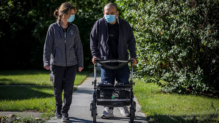 Marny Campkin, therapy assistant, walks with Sam Hutauruk, outside his home in Calgary.