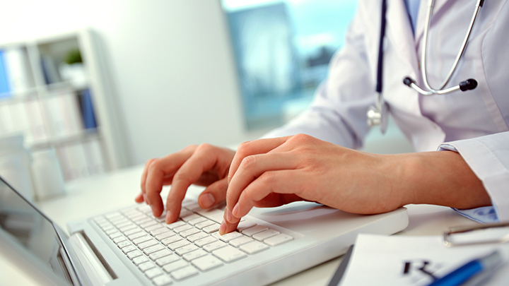 clinician typing on a laptop
