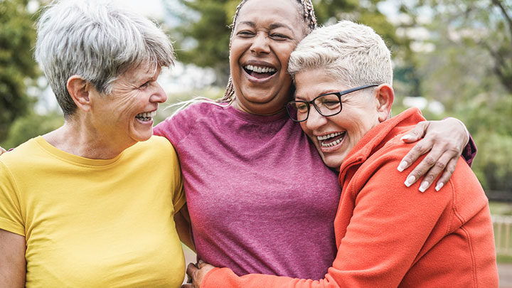 three senior women huddling and laughing