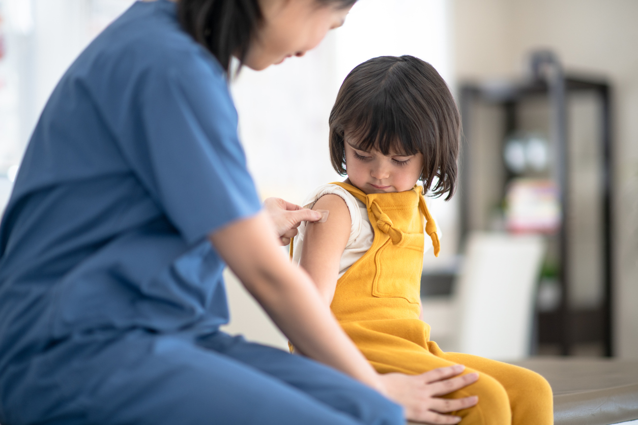 A nurse putting band-aid on a little girl.