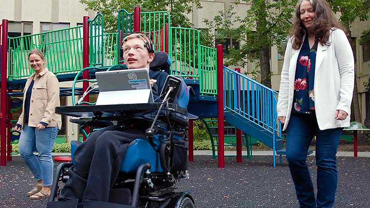Proud mom Rennie Froma, left, and occupational therapist Corinne Tuck watch on as Tristin Froma operates his power wheelchair using a brain-computer interface (BCI) and sensors connected  to his headrest at the Glenrose Rehabilitation Hospital. Patients with restricted mobility use BCI to play video games, move a robot covered in paint to create art, play music and, in Tristin’s case, to drive their wheelchair. 