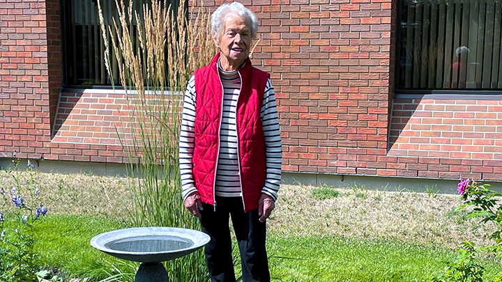 Pat Grayling, a long-time AHS volunteer, poses next to the garden named in her honour.