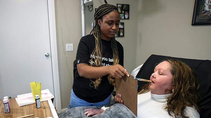 Carrie Morrison paints with help from nursing student/caregiver Aba Prah at her home in Lethbridge. The therapeutic recreation program at AHS sparked a creative passion for the quadriplegic patient.