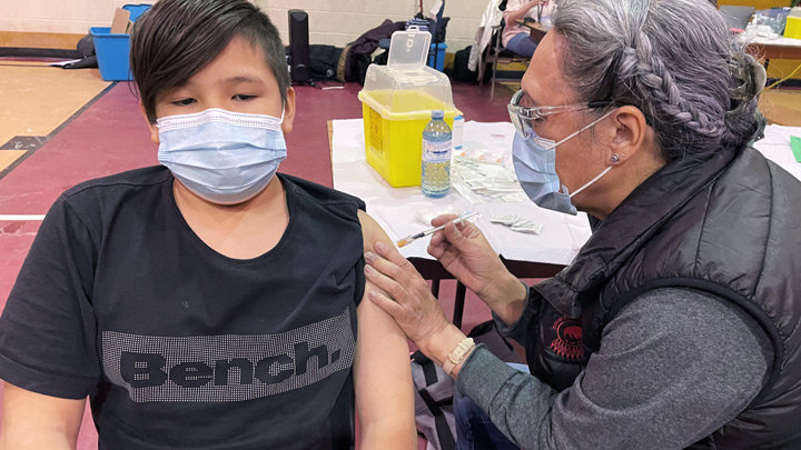 Eleven-year-old Kayson Creighton got his COVID-19 vaccination recently at a Sik-Ooh-Kotok Friendship Centre vaccine event in Lethbridge. At the centre, a big screen played movies for waiting families, adding to the festive atmosphere.