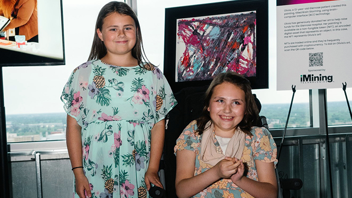 Lauren Terry stands alongside her sister Olivia at the Glenrose Rehabilitation Hospital Foundation’s Shining a Light event where Olivia’s painting, which she created using brain-computer interface (BCI) technology, is on display. The 13-year-old lives with Rett Syndrome. Olivia has restricted physical control of her hands but is able to express her creativity by wearing a headset that acts as a direct communication pathway between her brain's electrical activity and a Bluetooth robot.