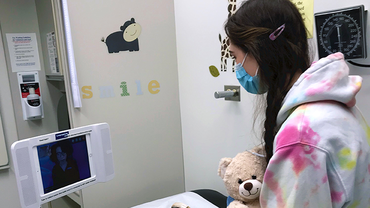 A young patient makes use a video link and an interpreter to ask questions about her health.