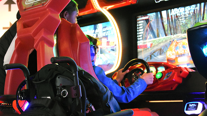Maverick Schulz boldly takes the wheel on a virtual race course as recreational therapist Shannell Corrodas-Brown checks out the action over his shoulder.