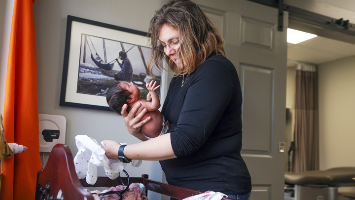 At the West Country Midwives clinic, Matheson holds a newborn during a postpartum visit – one of her many stops during her day caring for people throughout their pregnancy journey. 