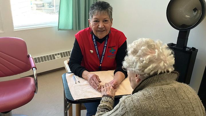 Paula Jack brings cheer, conversation and support to a long term care resident at the Milk River Health Centre.