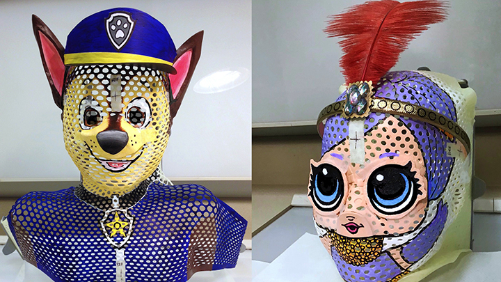 Alberta Health Services volunteer Marilyn Kimura paints fun faces onto the masks children wear while receiving radiation therapy. These two depict Chase from Paw Patrol and an LOL Doll.