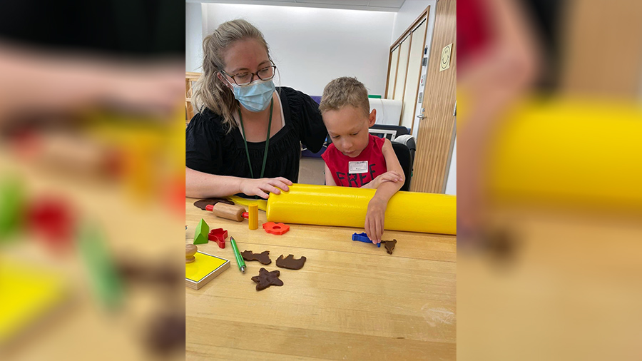 Pediatric OT Caitlin West guides families to engage in therapeutic activities as part of their regular activities, such as playing with toys, blowing bubbles or molding objects out of clay.