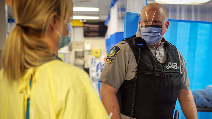 Peace officer Ryan Halford, right, talks with a nurse about a patient in Emergency at Peter Lougheed Hospital.