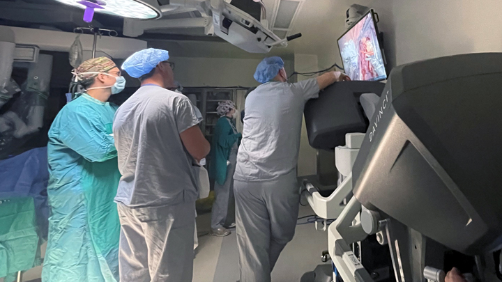 Dr. Max Levine controls robotic arms from a console as his University of Alberta Hospital team — Dr. Andrew Rasmussen, left, Dr. Blair St. Martin and Dr. Trevor Schuler — watch the procedure unfold.