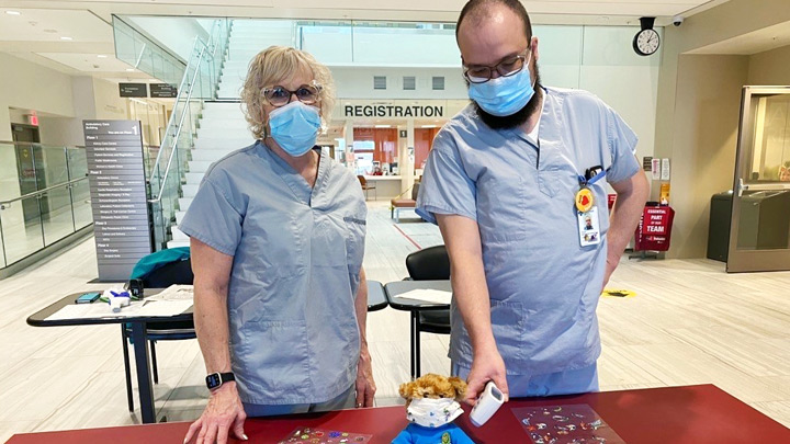 Screeners Wanda Fischer and Dean Halbert check their Teddy’s temperature at the entrance to Medicine Hat Regional Hospital.