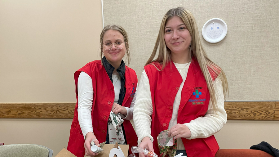 Martha Froese, left, and Isabella Neufeld fill stockings with treats and comfort items. The handmade stockings will be delivered to patients at the Taber Health Centre for Christmas.