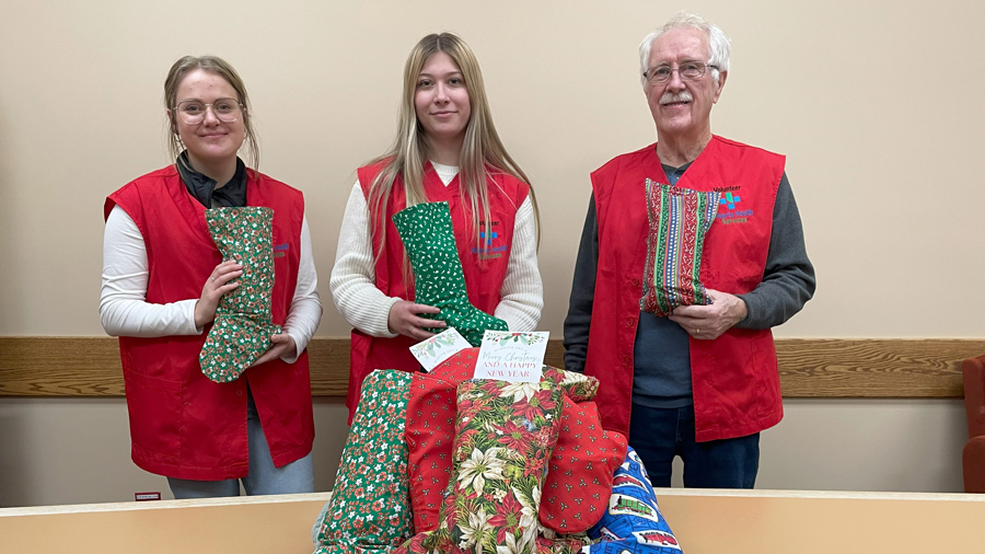 AHS volunteers, Martha Froese, left, Isabella Neufeld and Joe Constantine got together in early December at the Taber Health to fill the stockings made by the Hays Seniors quilters with gifts purchased by Volunteer Resources with funds raised by the Taber & District Health Foundation. 