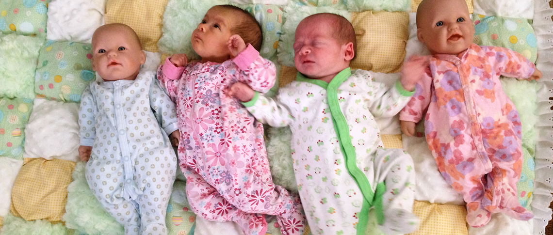 At five weeks old, Briana and Julian Houle pose with older sister Rowen’s dollies