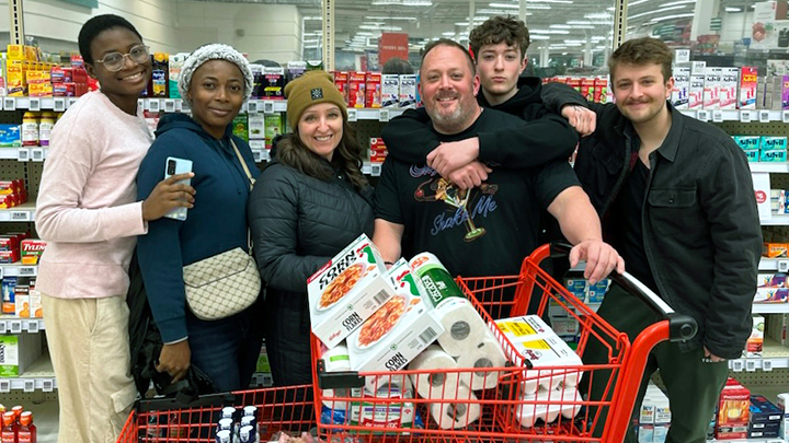 Wisdom Aderibigbe-Simeon, left, and Chinyere Mbadinuju stock up on staples for their new homes as they enjoy a trip to the local grocery store with the Rideout family, from left, Tennille, Steve, Nathan and Lucas.